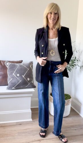 A woman showcasing how to look expensive on a budget by pairing affordable pants with a designer jacket bought on consignment, creating a polished and stylish outfit